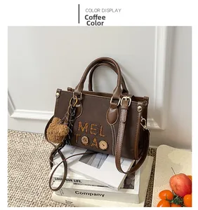 Détail du sac cabas marron café avec logo MELTOAO et breloque ours en peluche sur livres