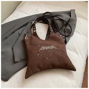 Detail of a dark brown suede tote bag featuring silver punk metal accents and rivets