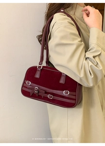 Burgundy velvet shoulder bag with bow detail and leather buckle shown on model in a retro style