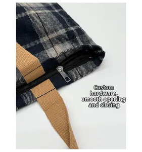 Detail of silver metal zipper and blue plaid fabric on a large shoulder bag