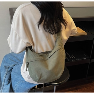Close-up of military green canvas crossbody bag with drawstring and zipper detail