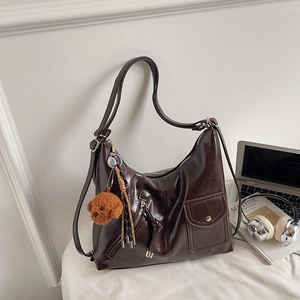 Detail of a large dark brown tote bag with glossy finish and cute puppy plush charm