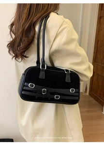 Detail of black bowling bag with bow and silver buckle straps worn by a model