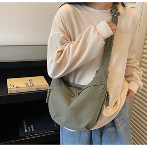 Detail of dark green canvas crossbody bag with adjustable wide strap on model