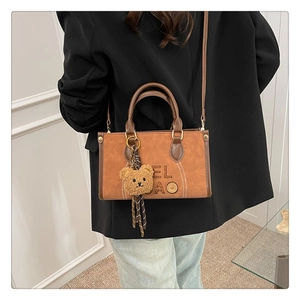 Vue détaillée du sac à main vintage en cuir avec un charmant petit ours et sa bandoulière