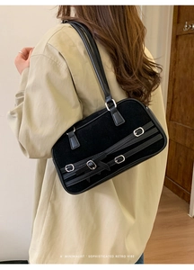 Detail of a black retro shoulder bag in suede and leather with metallic buckles and straps