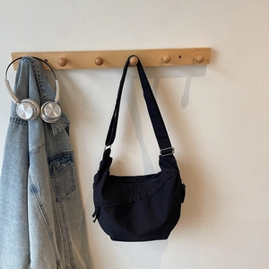 Macro shot of black minimalist canvas crossbody bag with side drawstring and metal zipper details