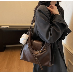 Detail view of coffee brown vintage tote bag with retro texture and bear charm accessory