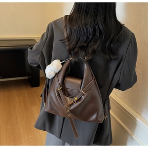 Detail of vintage brown shoulder bag with faux fur pompom and adjustable metal buckle strap