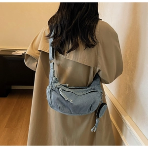 Détail du grand sac demi-lune en jean avec petite pochette assortie et bandoulière