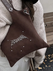 Brown suede hobo tote bag with silver studs and metal hardware in a casual outdoor setting