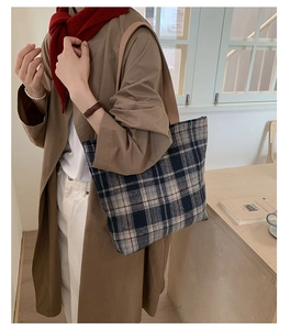 Detail of vintage wool plaid tote bag with brown leather strap in an autumn outfit context