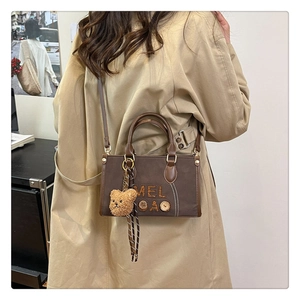Sac bandoulière rétro marron avec charm ours sur un mannequin en trench kaki
