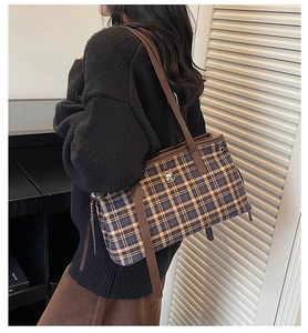 Detail of tartan tote bag with teddy bear patch and leather straps on shoulder