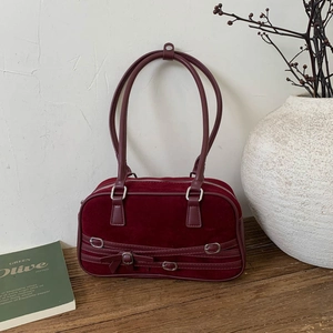 Detail of burgundy suede bowling bag with silver hardware and decorative ribbon straps