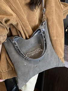 Grey suede tote bag with metallic studs and chain detail shown as a crossbody