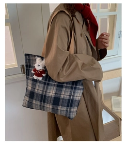 Detail of blue plaid tweed tote bag with cute dog pendant and brown strap on shoulder