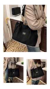 Detail of black tote bag featuring luxury gold chain straps and leather logo patch