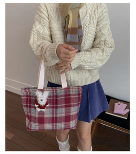 Detailed texture of red and grey plaid woven tote bag with a cute white bunny pendant charm