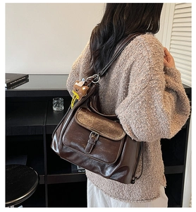 Close-up of dark brown leather handbag with glittery flap and cute plush bear charm
