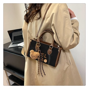 Détail d'un sac bandoulière rétro en toile avec garniture cuir et pendentif ours