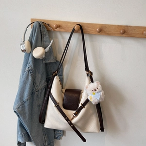 Detail of color-block tote bag with plush bear charm and premium faux leather texture