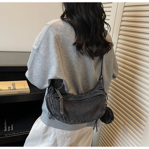 Vue détaillée du sac croissant en denim gris foncé porté en bandoulière décontractée