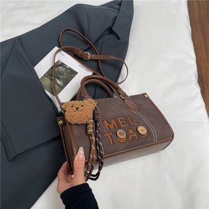 Détails du sac cabas marron vintage avec broderie de lettres et breloque ours