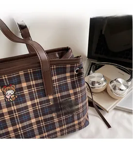 Close-up of vintage plaid tote bag featuring bear embroidery and leather handles