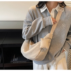 Dettaglio della borsa a tracolla trapuntata beige con tracolla regolabile sul modello