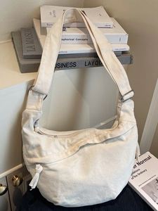 Minimalist cream canvas half-moon crossbody bag with wide adjustable strap and drawstring