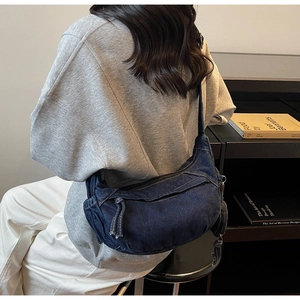 Détail d'un grand sac bandoulière en denim bleu foncé avec des coutures contrastées