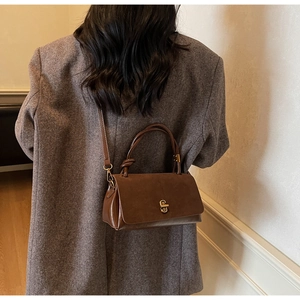 Close-up of vintage brown crossbody bag with gold metal infinity twist lock detail