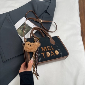 Détail du sac à main en toile avec finitions cuir, boutons bois et pendentif ourson