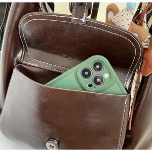 Detailed close-up of durable front pocket on dark brown faux leather backpack with phone