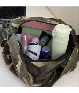 Détail de l'intérieur spacieux d'un sac en toile camouflage avec divers objets du quotidien
