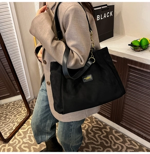 Detail of black large capacity tote bag with leather strap and gold chain decoration