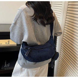 Détail du grand sac croissant en denim bleu foncé avec surpiqûres et porte-monnaie
