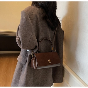 Close-up of brown textured leather crossbody bag with elegant gold twist-lock closure