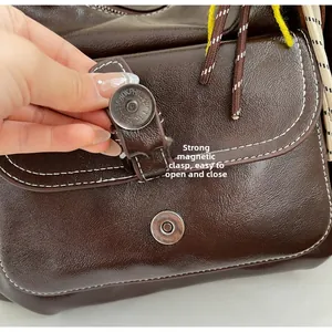 Detail of a brown leather bag showing the magnetic snap closure and contrast stitching