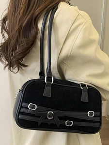 Minimalist black bowling shoulder bag with suede texture and buckle straps on a model