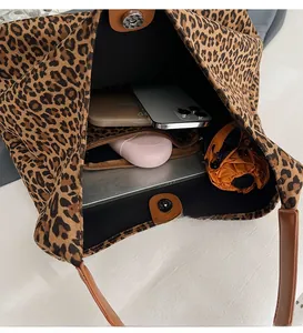 Detail view of leopard print tote bag interior with multiple items and metal snap button