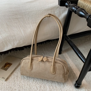 Detailed texture of a beige suede cylindrical baguette bag with sleek dual handles