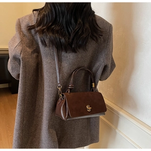 Brown vintage leather handbag with gold lock shown on model in urban minimalist setting
