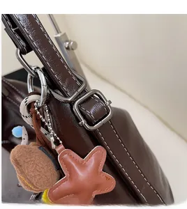 Detail of dark brown leather bag showing adjustable metal buckle and cute star charm