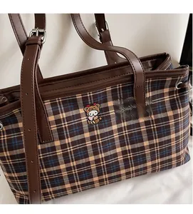 Detail of classic plaid tote bag with cute bear embroidery and brown leather handles
