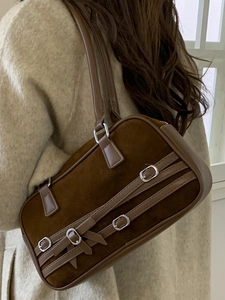Brown suede bowling bag with leather trim and silver metal buckles shown on a model