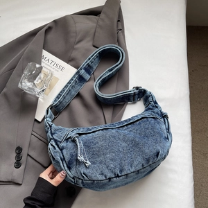 Vue détaillée d'un sac bandoulière en denim bleu avec bandoulière réglable sur un blazer