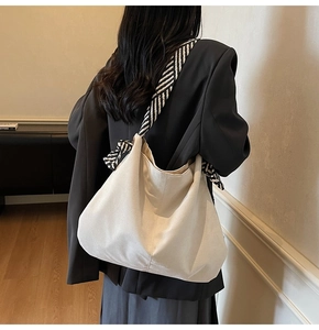 Detail of off-white hobo tote bag with striped shoulder strap and bow ribbon accent