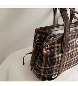 Detail of vintage plaid tote bag featuring leather drawstring side and refined embroidery